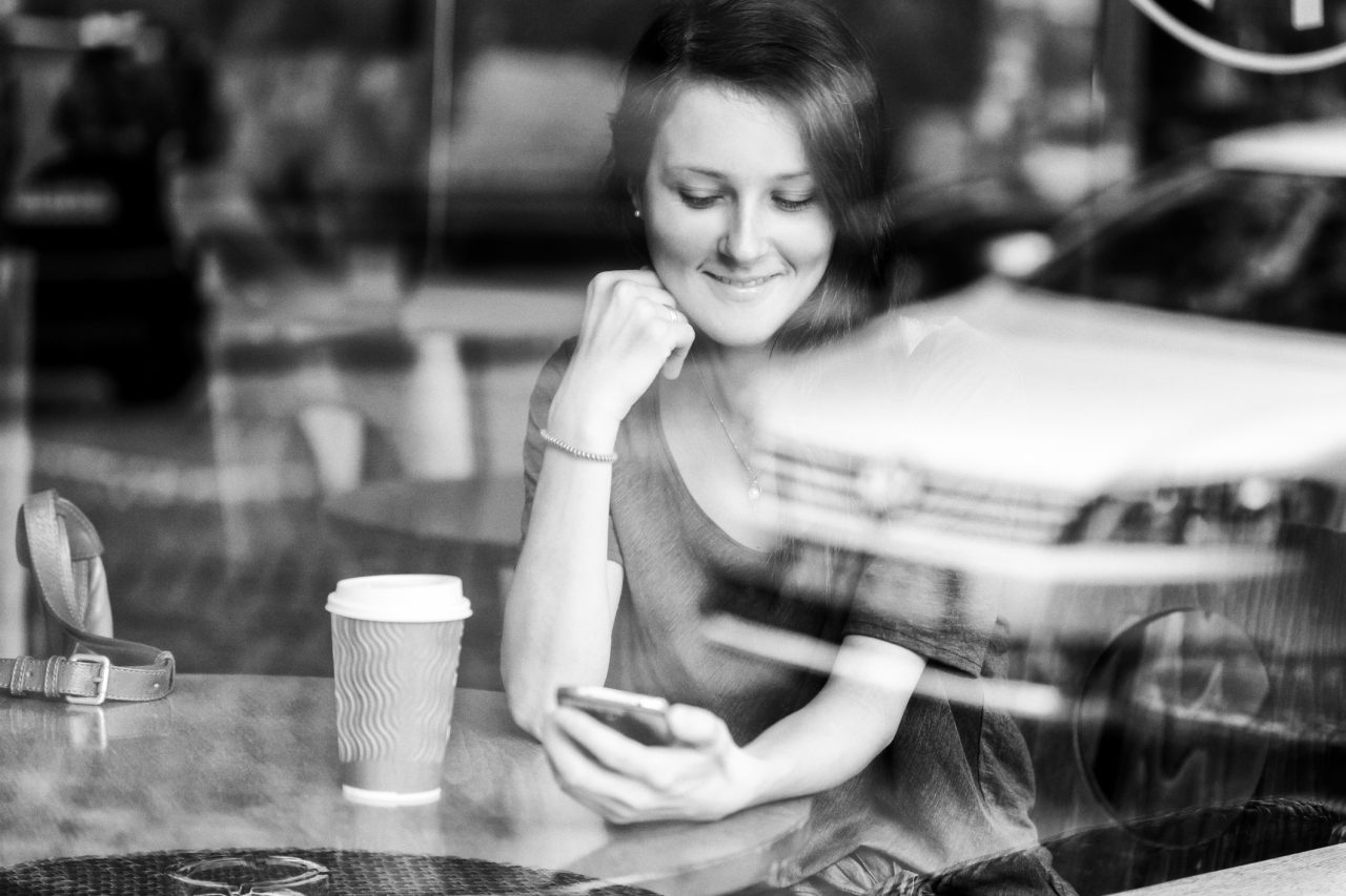 Dame som sitter på en cafée og ser på smarttelefon