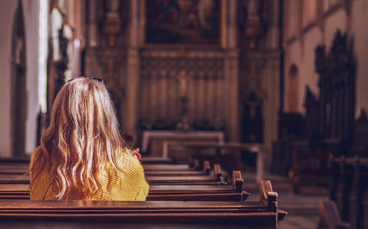 Jente som ber en bønn i en kirke