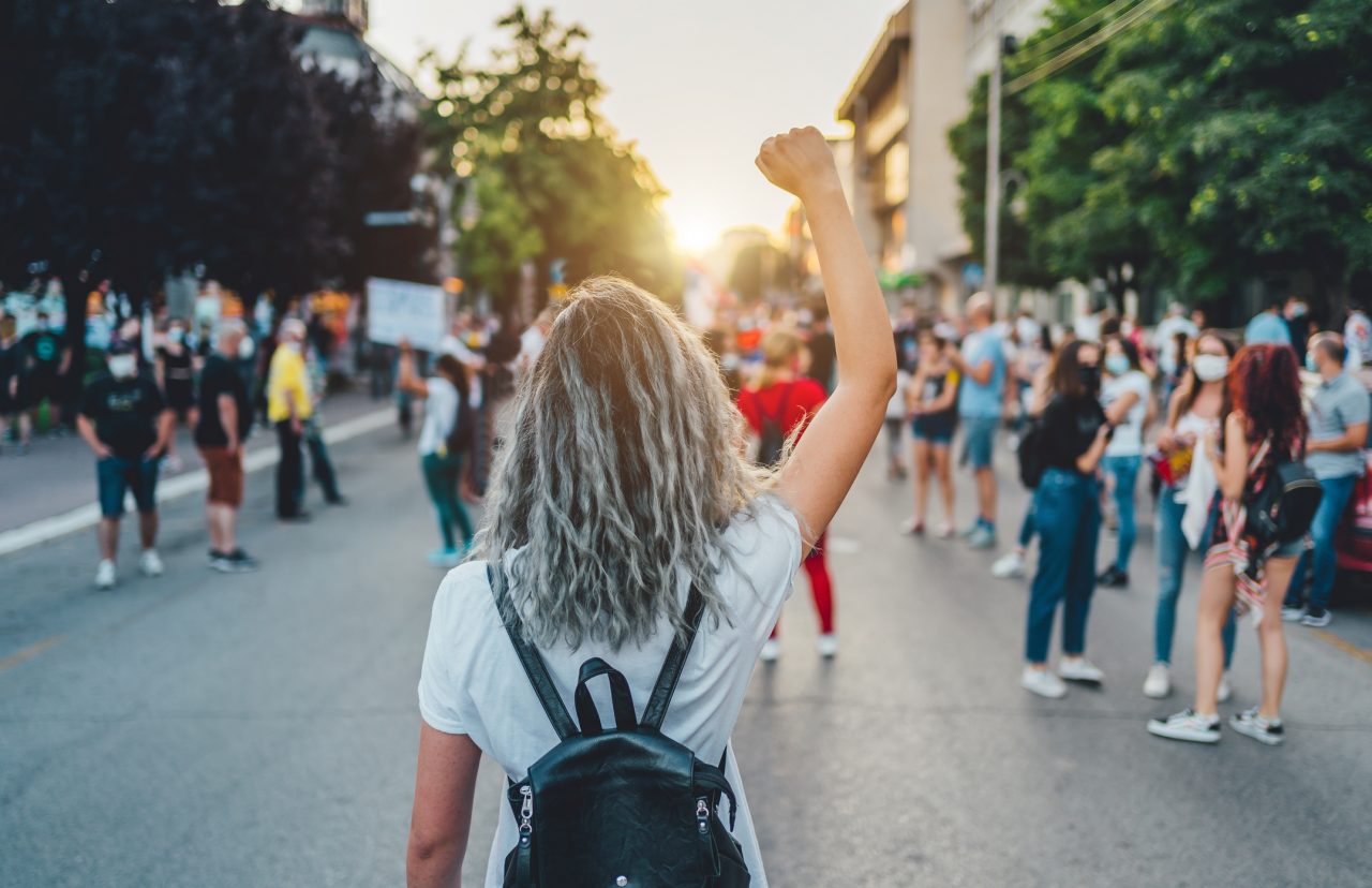 Ung kvinne med hevet knyttneve i gatene under en streik, eller protest.