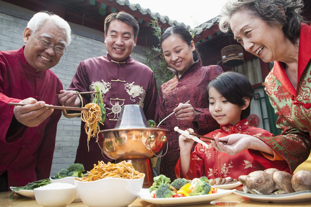 En kinesisk familie spiser kinesisk mat kledd i tradisjonell folkedrakt