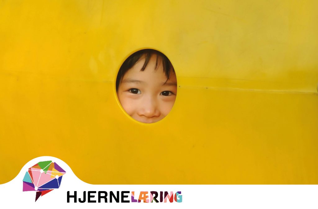 Boy peeking out of a hole in a yellow sculpture