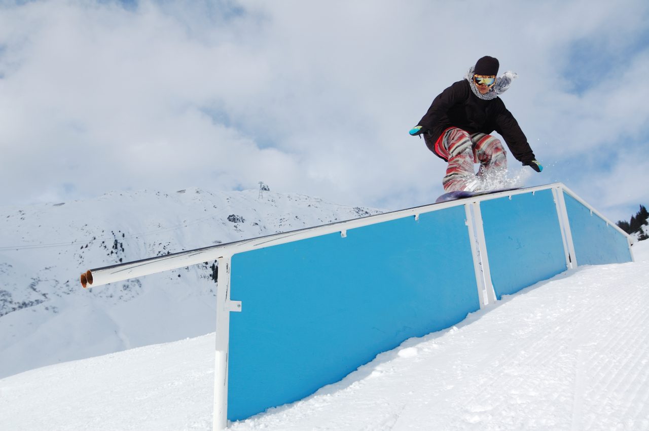 Ung snowboarder kjører på en rail i snøen.