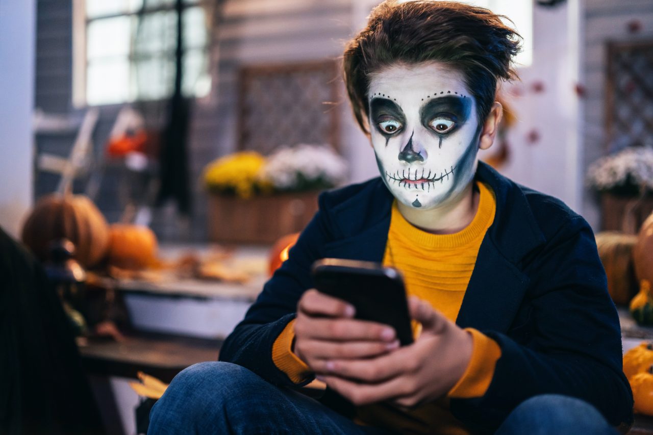 Halloween-gutt med mobiltelefon