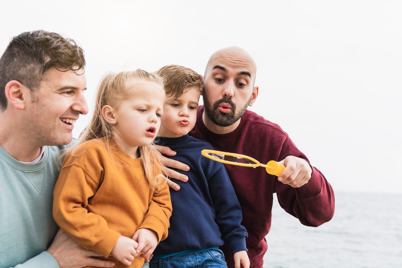 En familie på to menn og to barn leker med såpebobler.