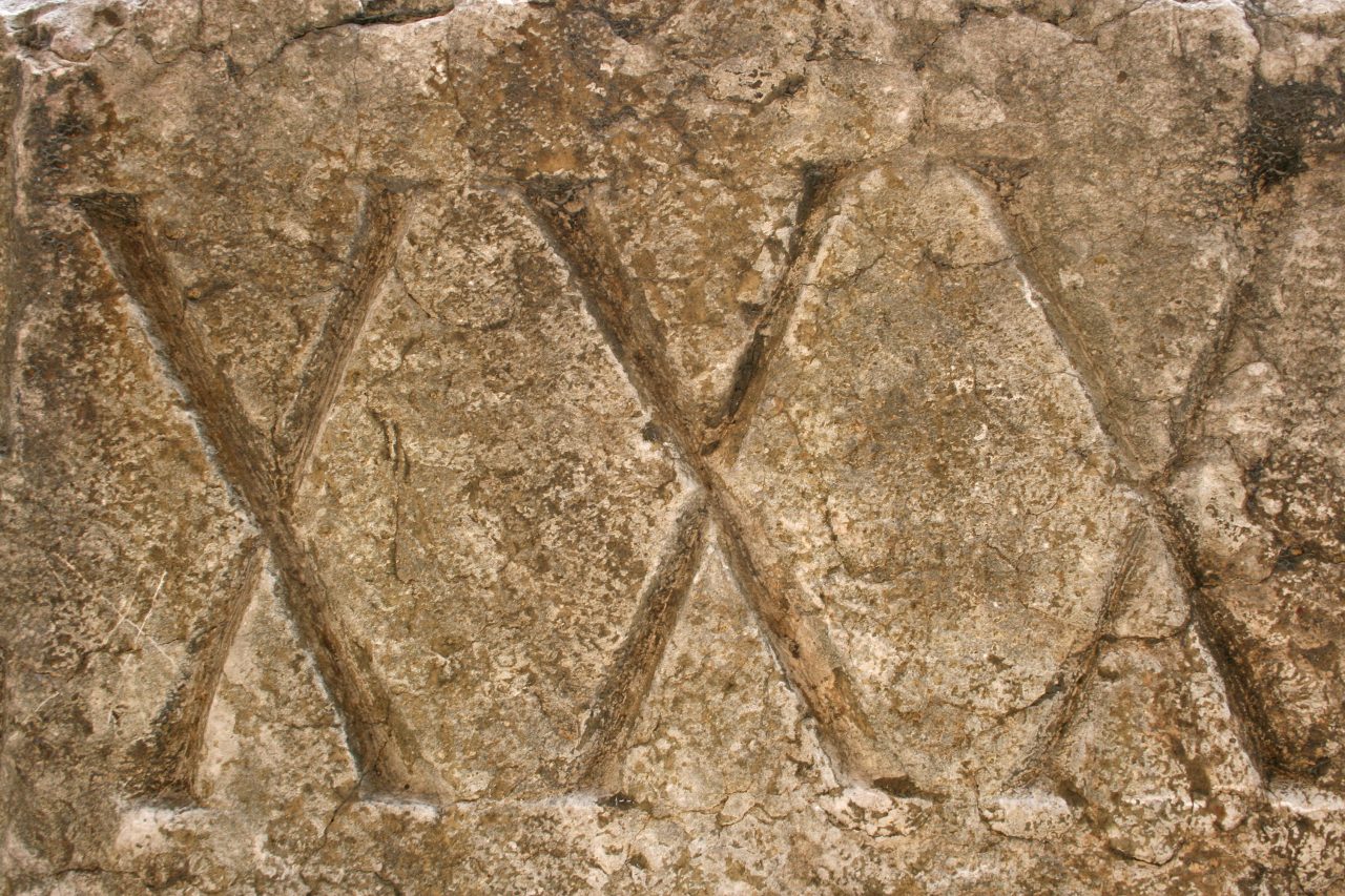 Tre X-er hogget inn i stein.