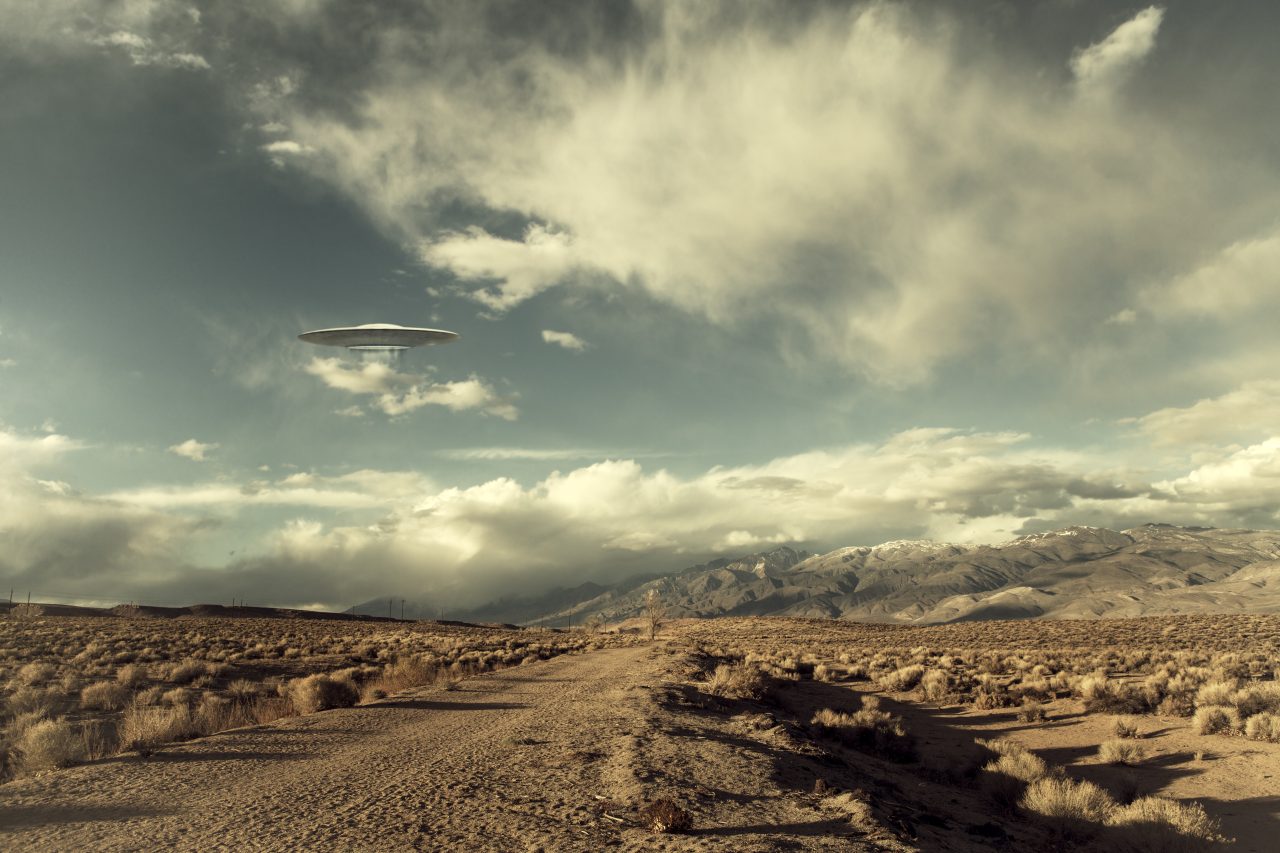 En UFO svever over et ørkenlandskap.