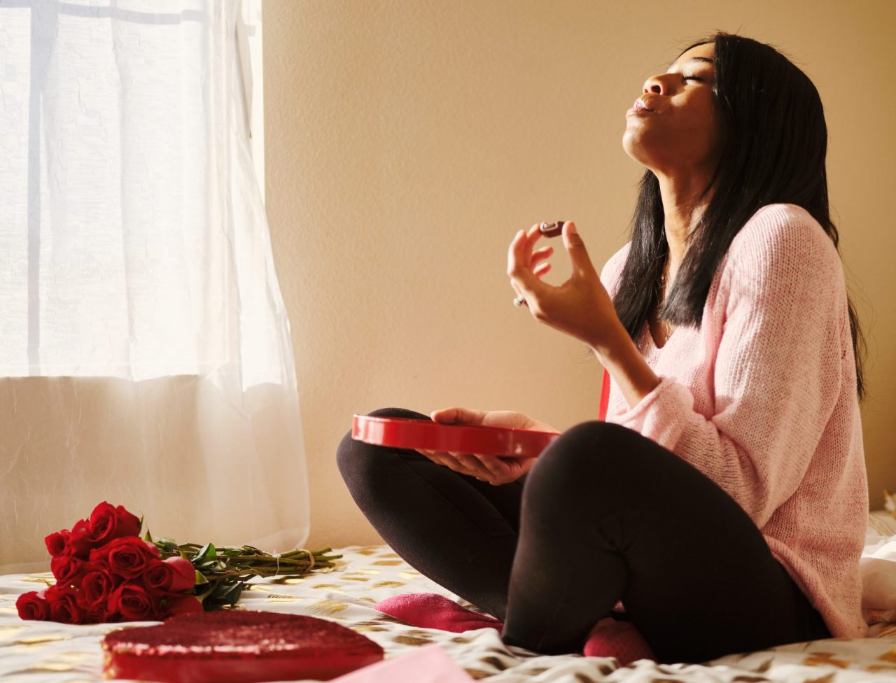 En dame sitter alene og koser seg med valentines sjokolade