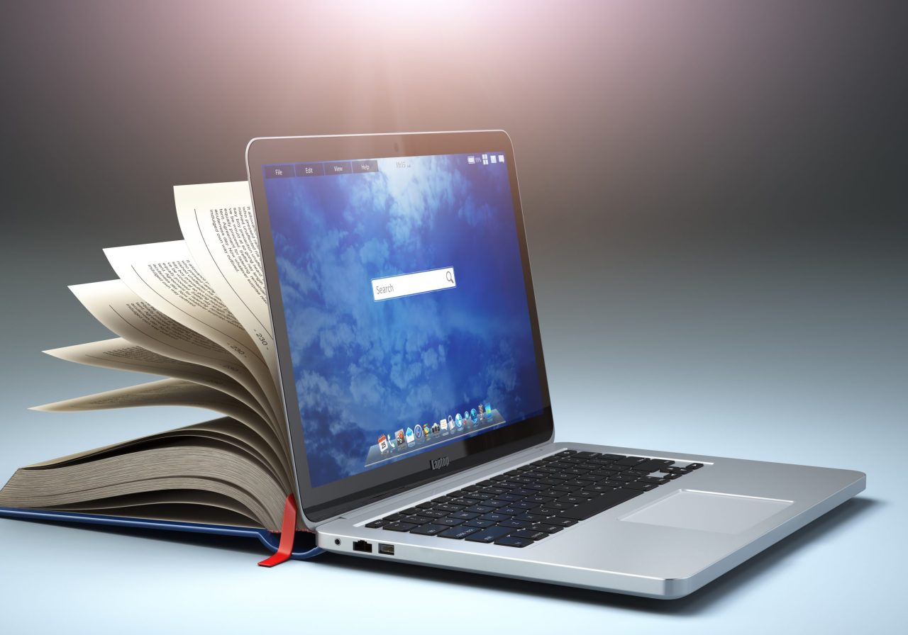 Åpen laptop med halv åpen bok bak skjermen som et symbol for digitalisering.