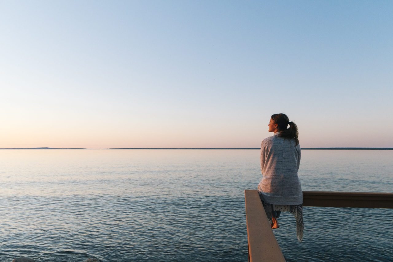 En dame som sitter og ser utover sjøen