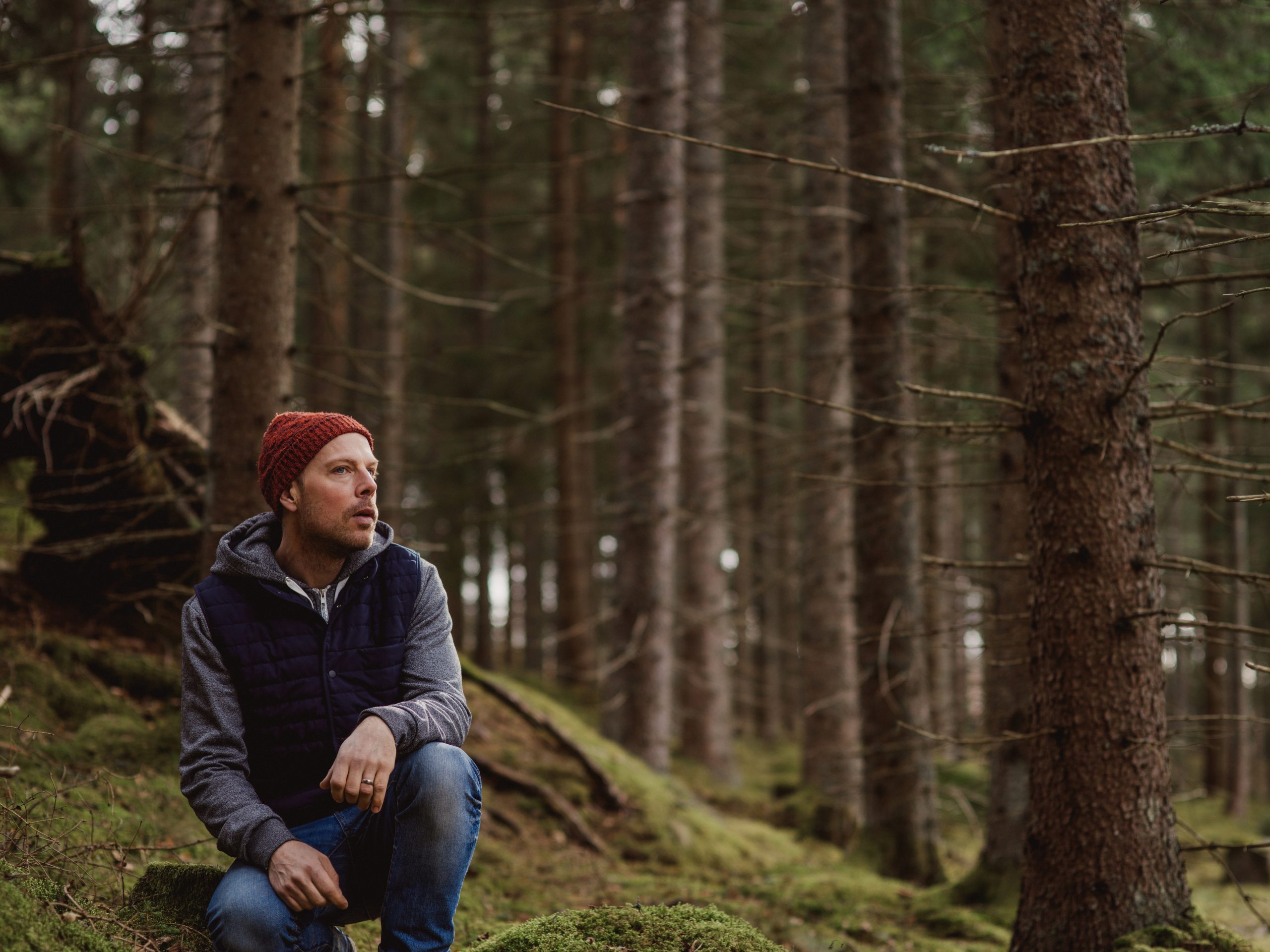 Mann sitter på knærne å slapper av i skogen