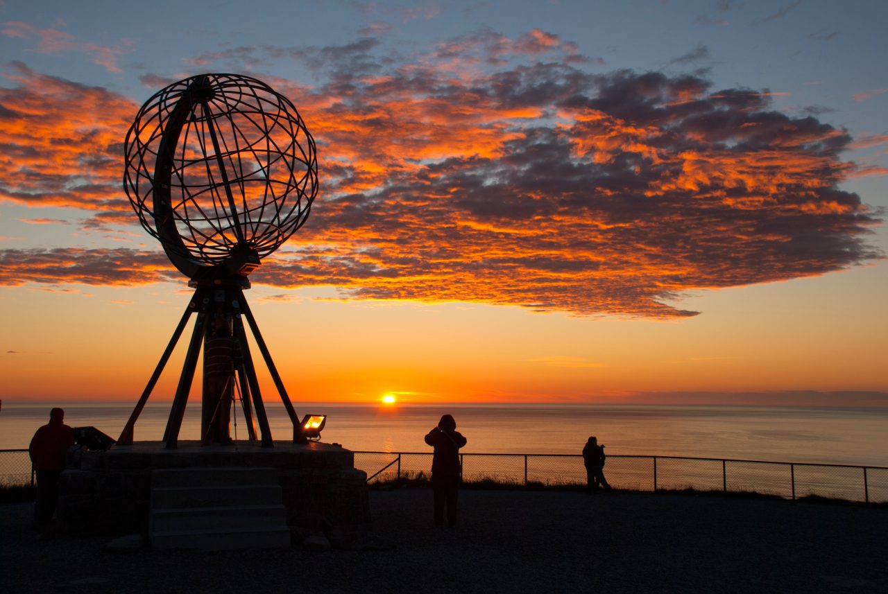 Den kjente globusen på Nordkapp med fargesprakende solnedgang i bakgrunnen.