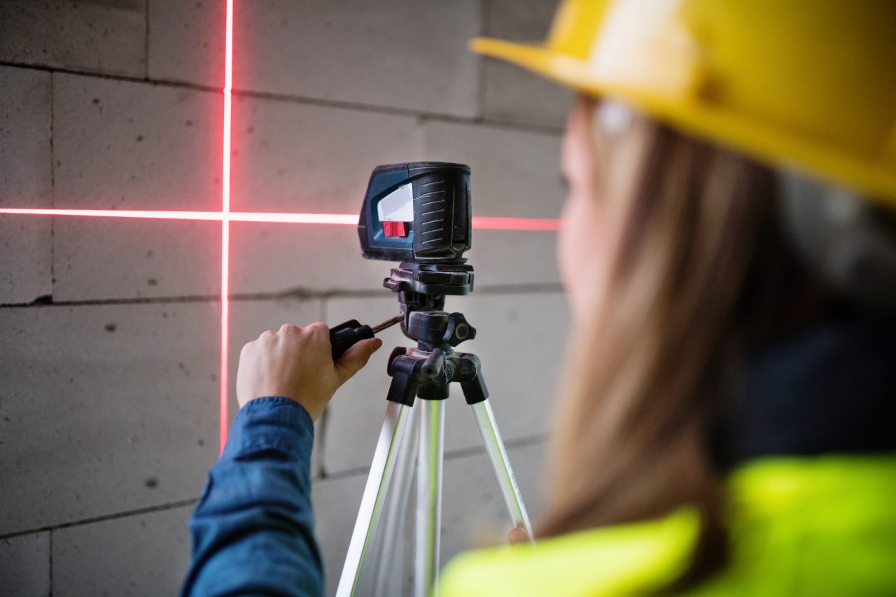 Bygningsarbeider bruker laser for å gjøre nøyaktige målinger på en murvegg.