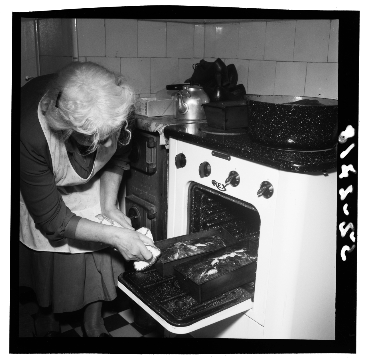 Gammel dame tar baksten ut av ovnen
