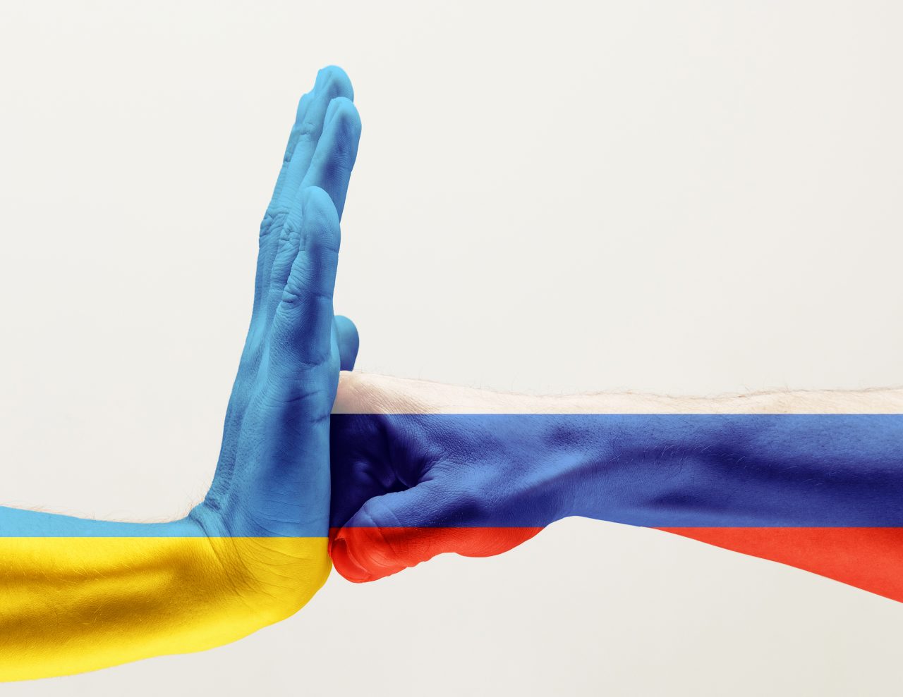 Knyttneve malt i fargene til Russland slår en flat hånd malt med fargene til Ukraina.
