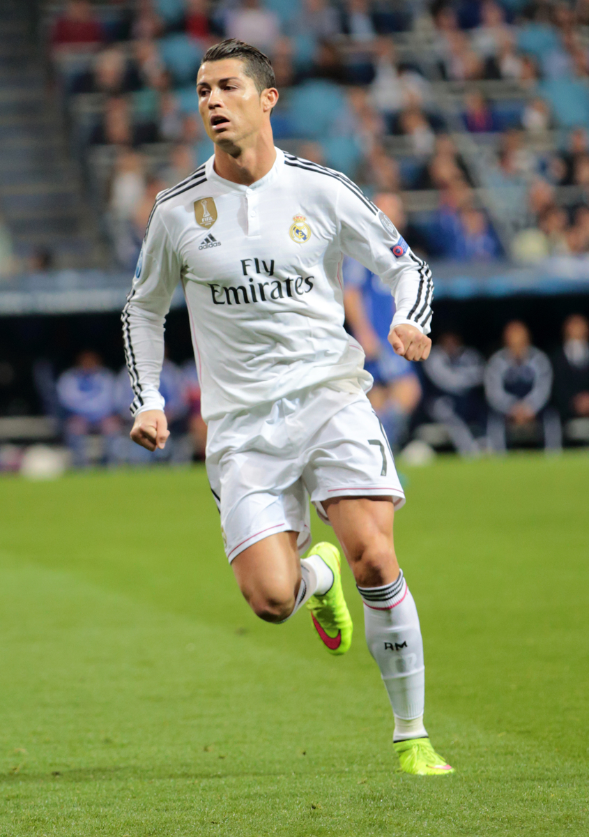 Christiano Ronaldo i hvit drakt løper på grønn fotballbane.