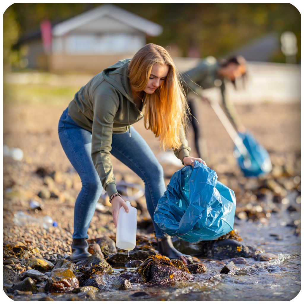 Jente rydder plast på stranden