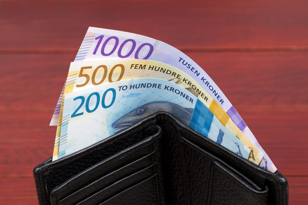 Norske pengesedler stikker opp fra en sort lommebok i skinn.