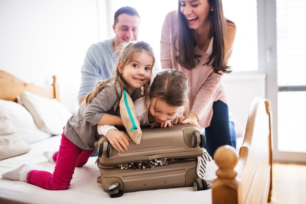 Familie på to barn og to voksne pakker koffert.