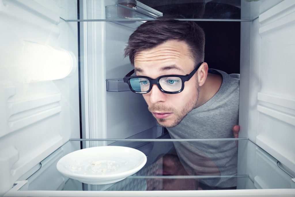 Mann ser fortvilet inn i et tomt kjøleskap