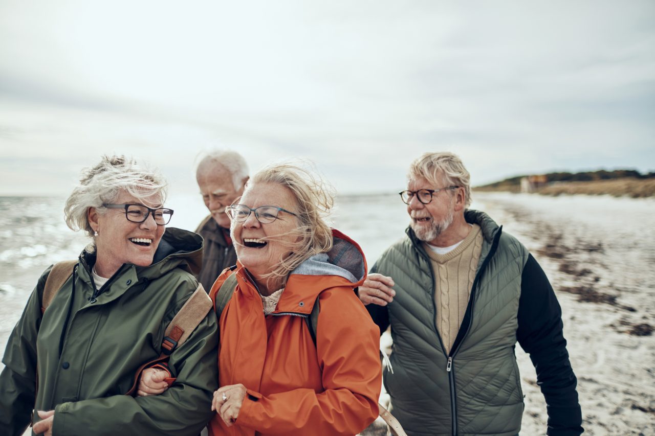 Eldre mennesker går tur langs en strand.