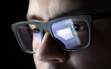Gjenskinn av internett i en manns brilleglass