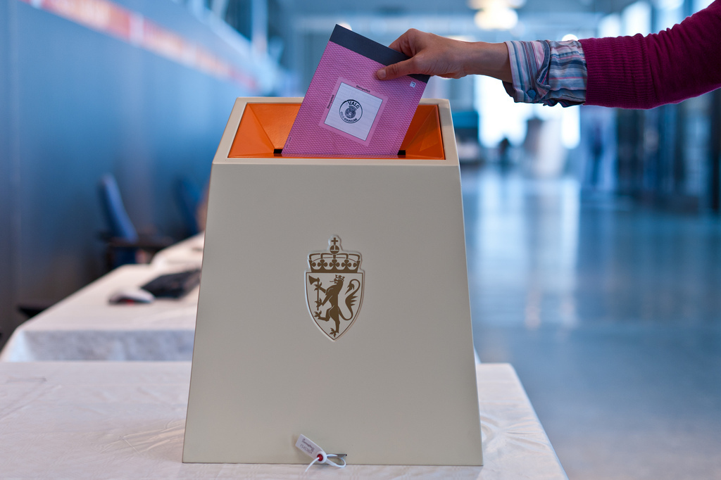 Bilde av en hånd som slipper en stemmeseddel ned i en valgurne.