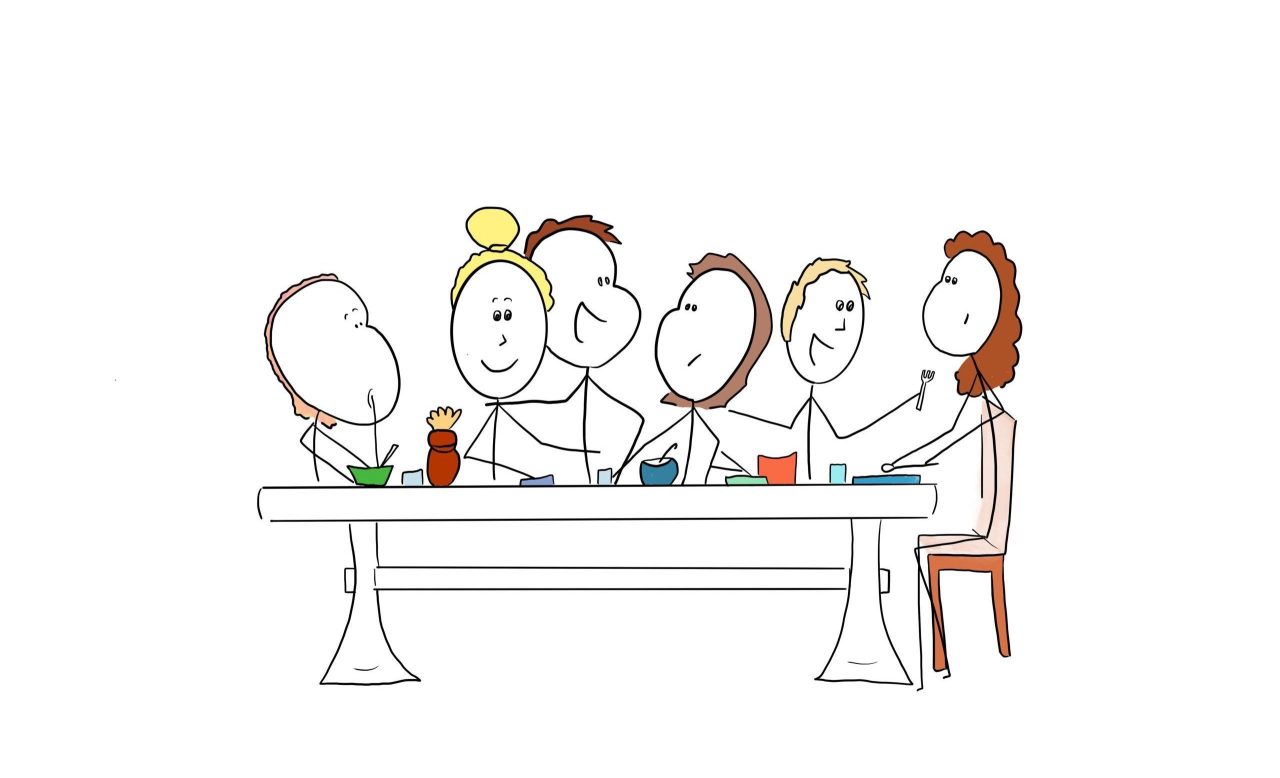 Six people sitting around a table talking and having dinner.