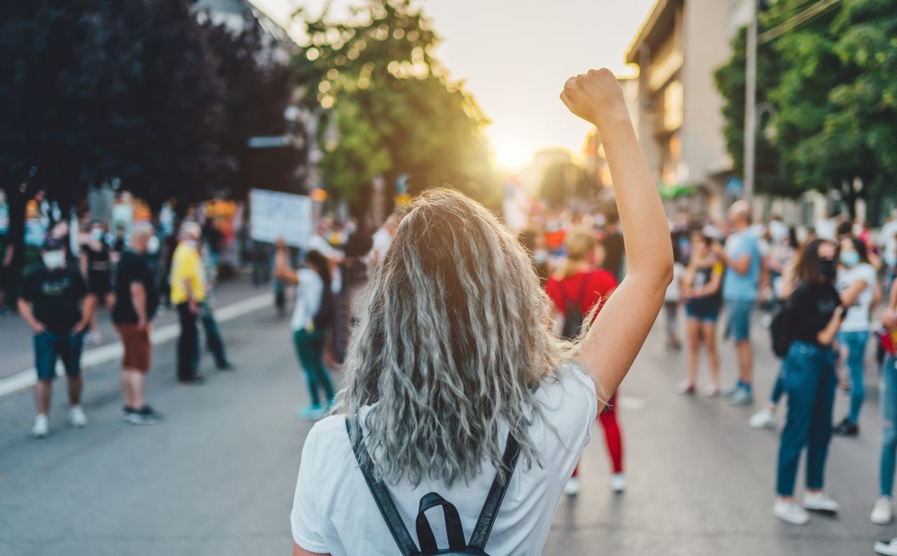 Ung kvinne med hevet knyttneve i gatene under en streik, eller protest.