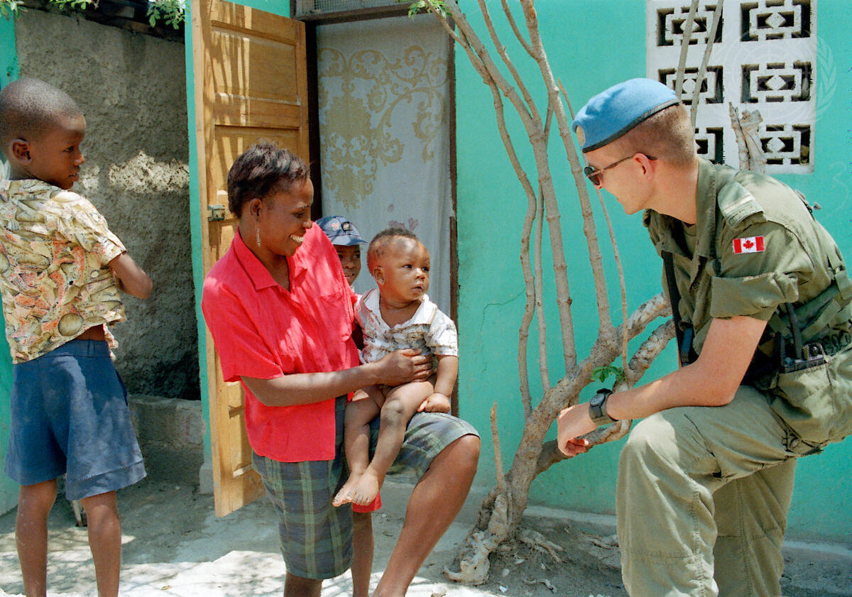 FN-soldat snakker med tre barn.