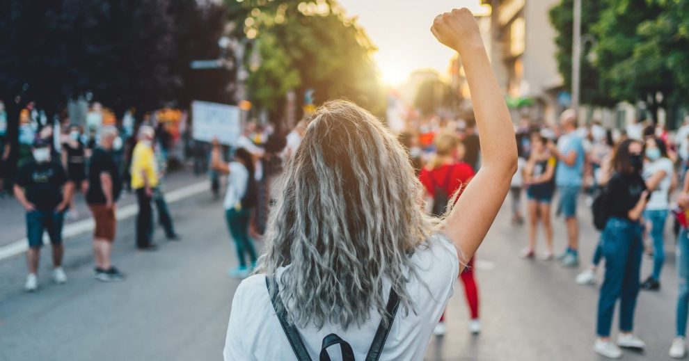 Ung kvinne med hevet knyttneve i gatene under en streik, eller protest.