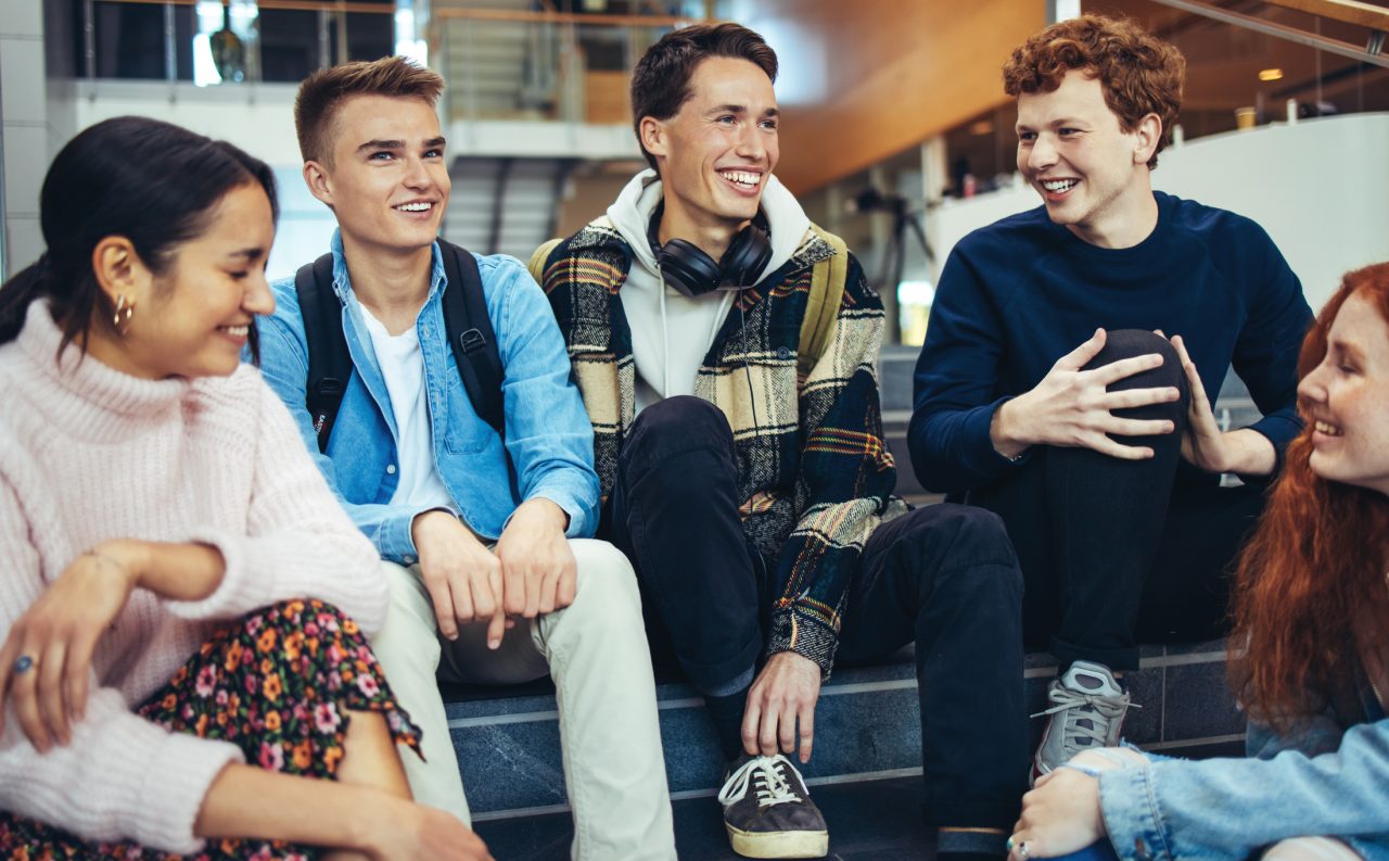 En gruppe studenter som sitter i en trapp inne på skolen og snakker