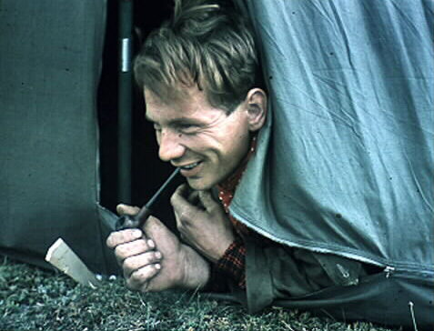 Paulus Utsi stikker hodet smilende utfra teltduken med en pipe i hånda