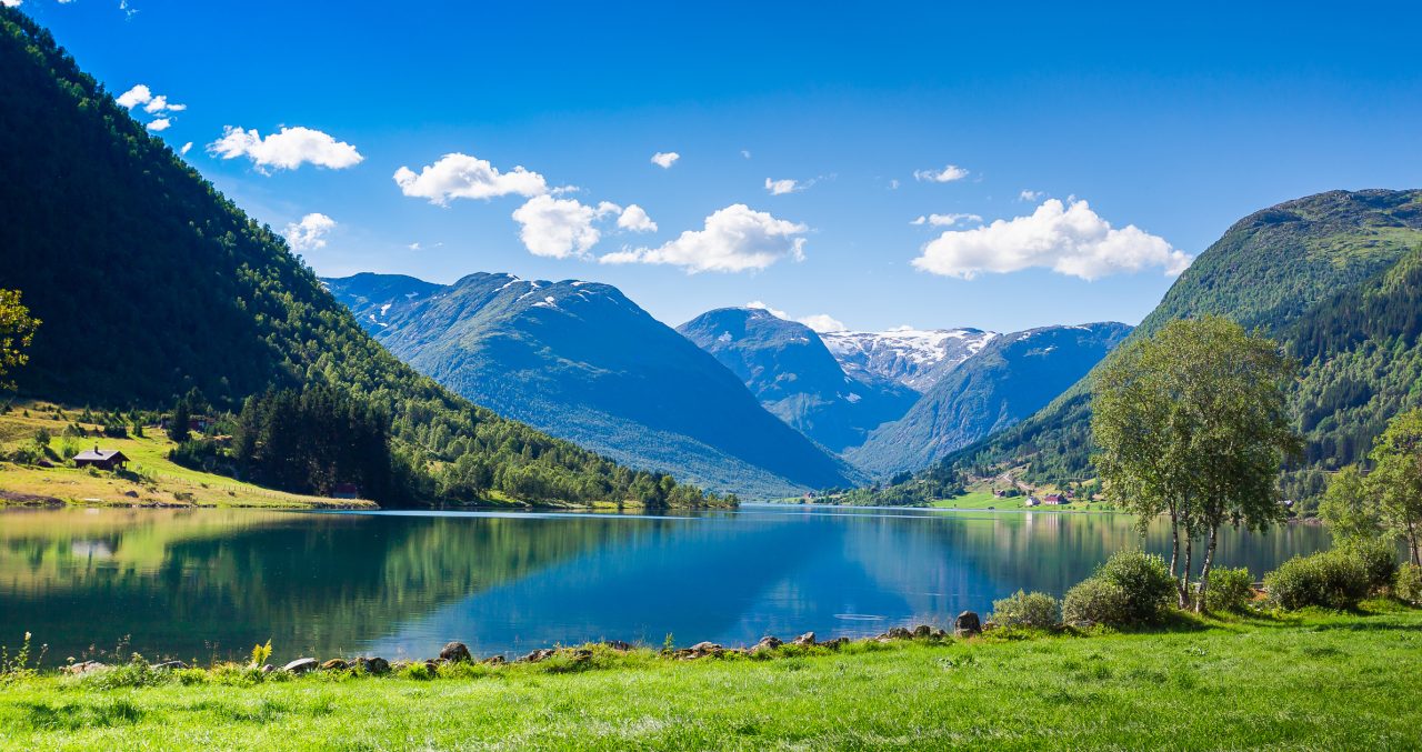 En rolig fjord mot en blå himmel i en dal i Sogndal