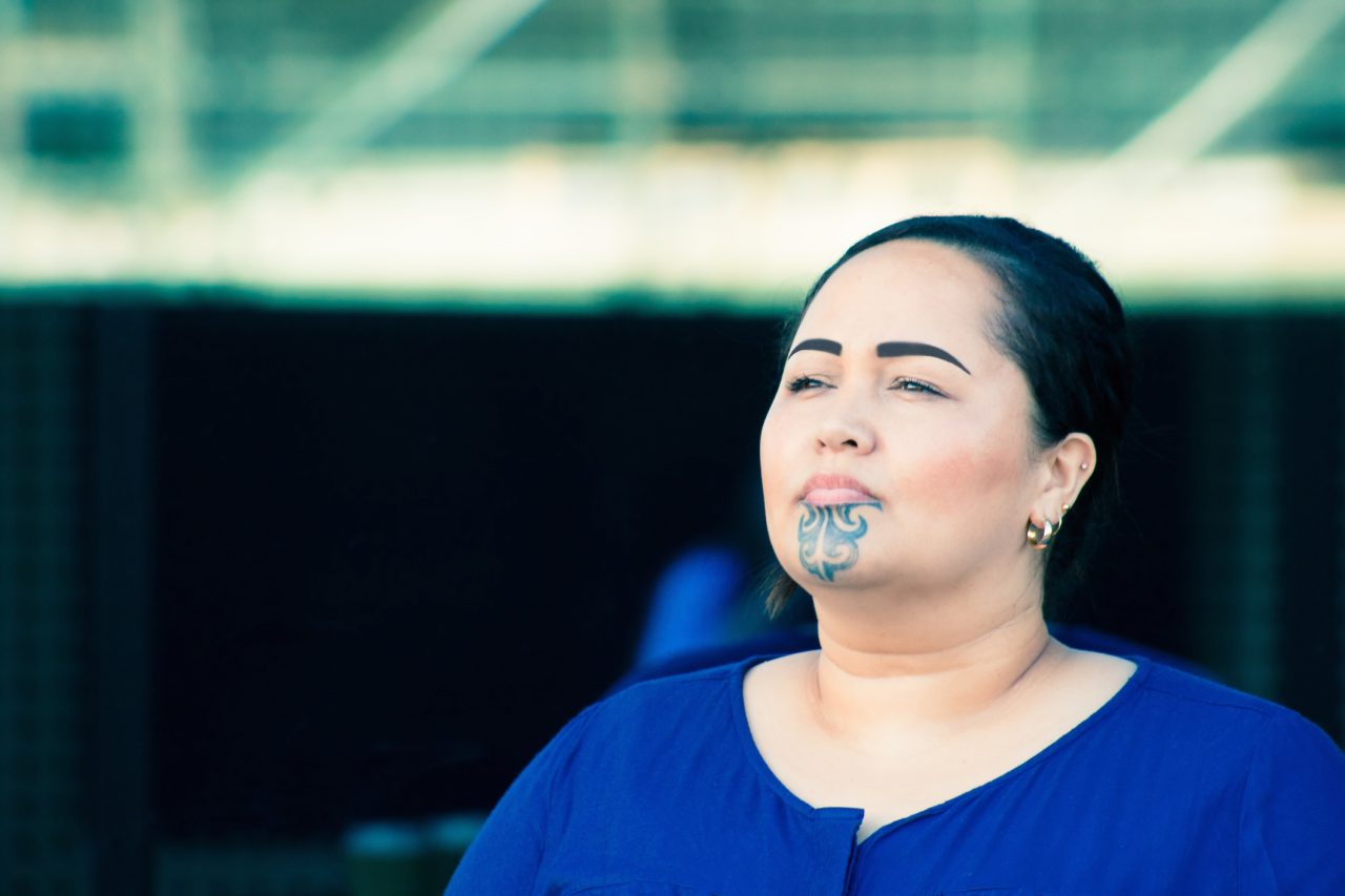 Close up portrait of a beautiful Maori businesswoman outdoors in the workplace with traditional tattoo on her chin