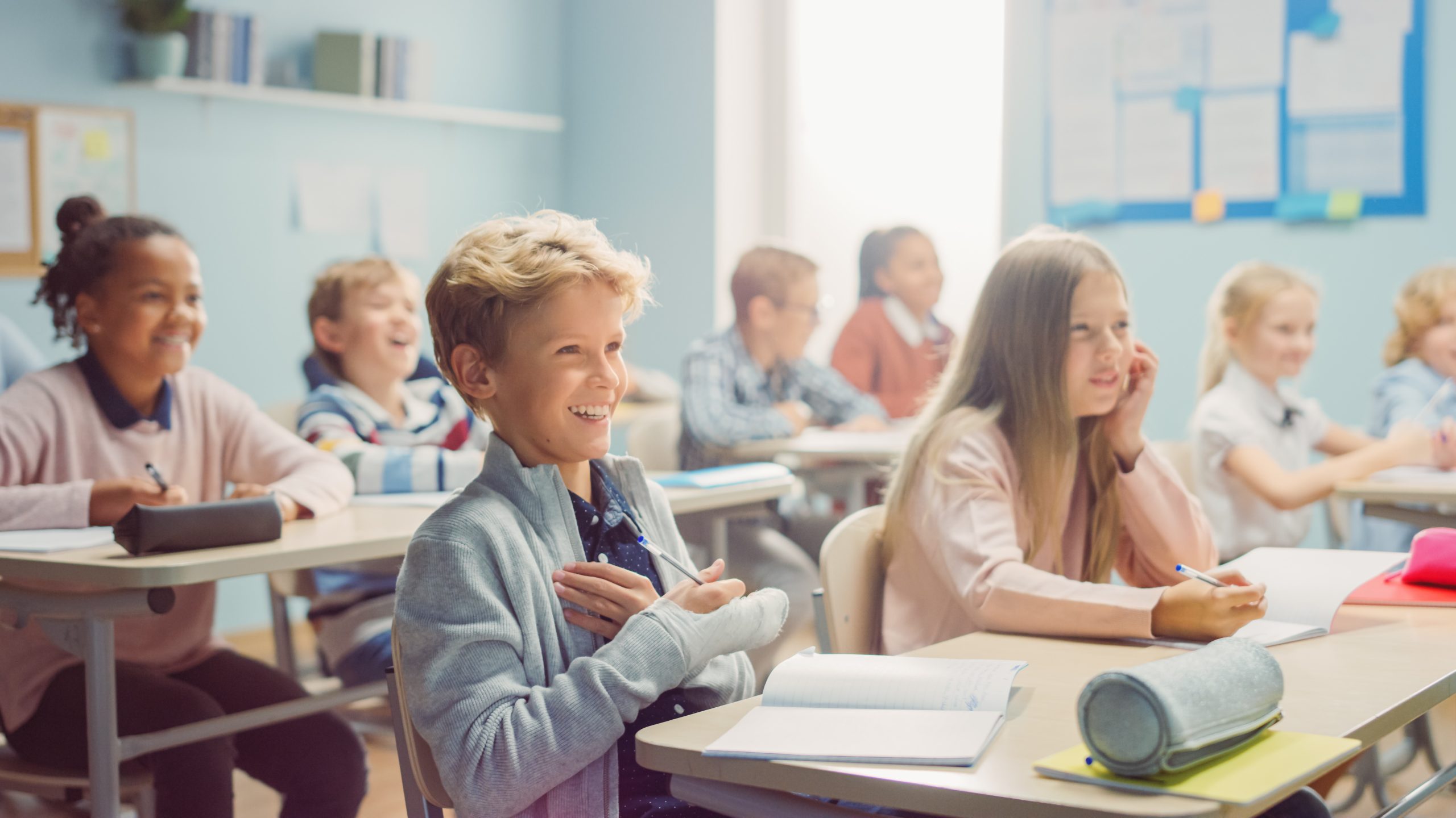 En klasse fra mellomtrinn sitter ved pultene sine og smiler og ler. De er glade for å ha faget norsk.