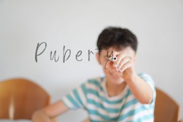 Gutt som skriver Pubertet på et vindu.