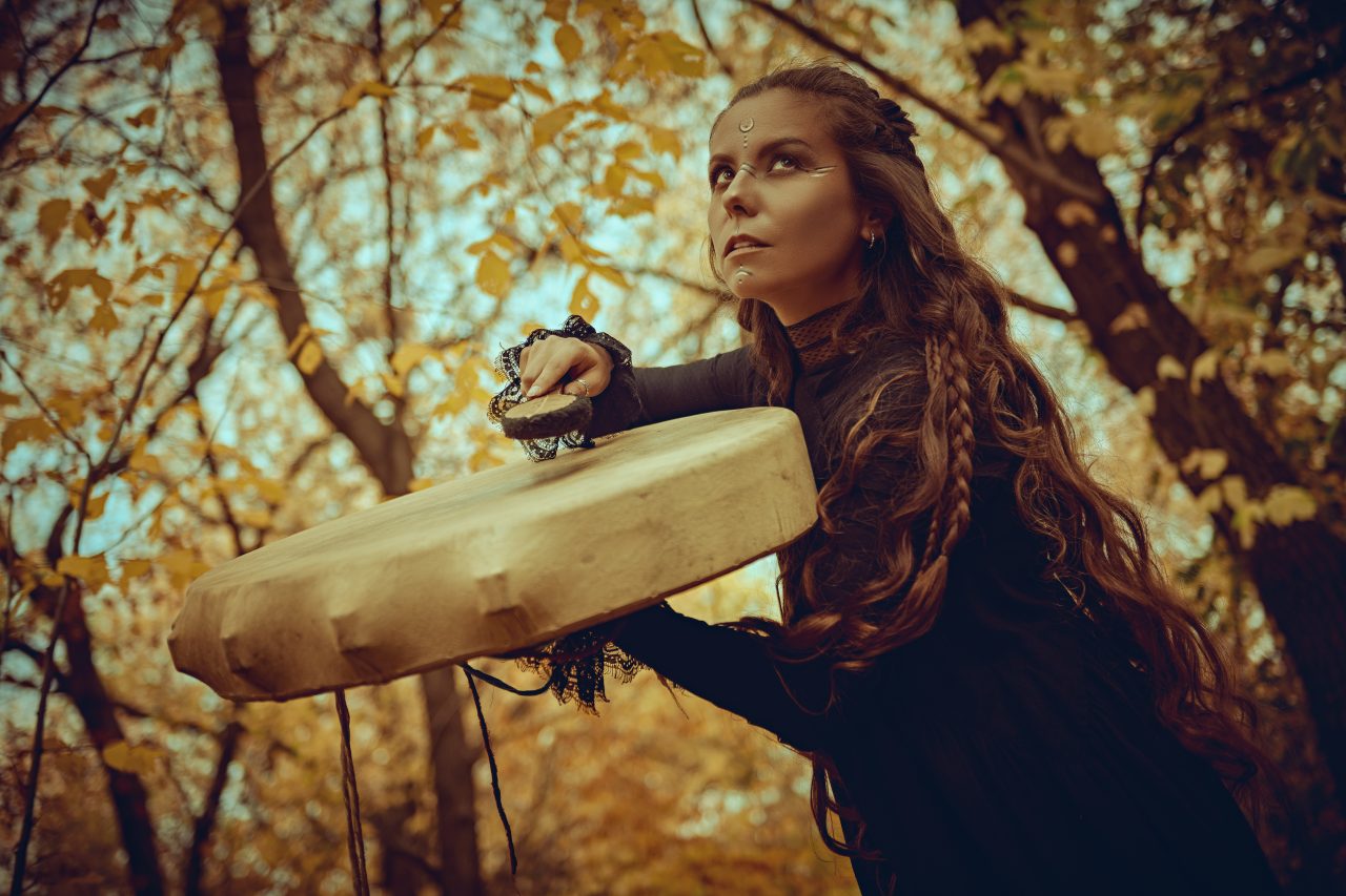 Ung kvinne som trommer og danser i skogen