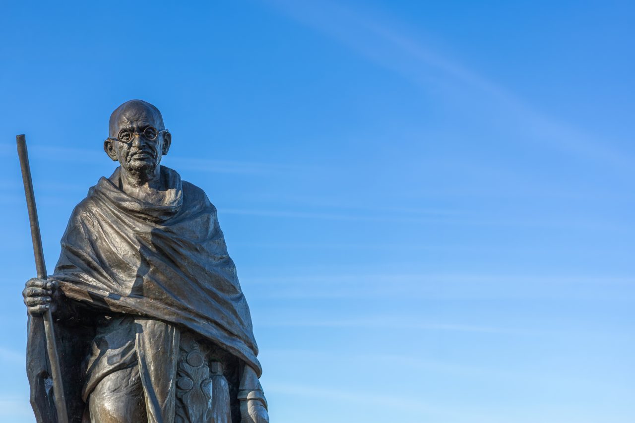 En statue av Mahatma Gandhi mot en klar blå himmel