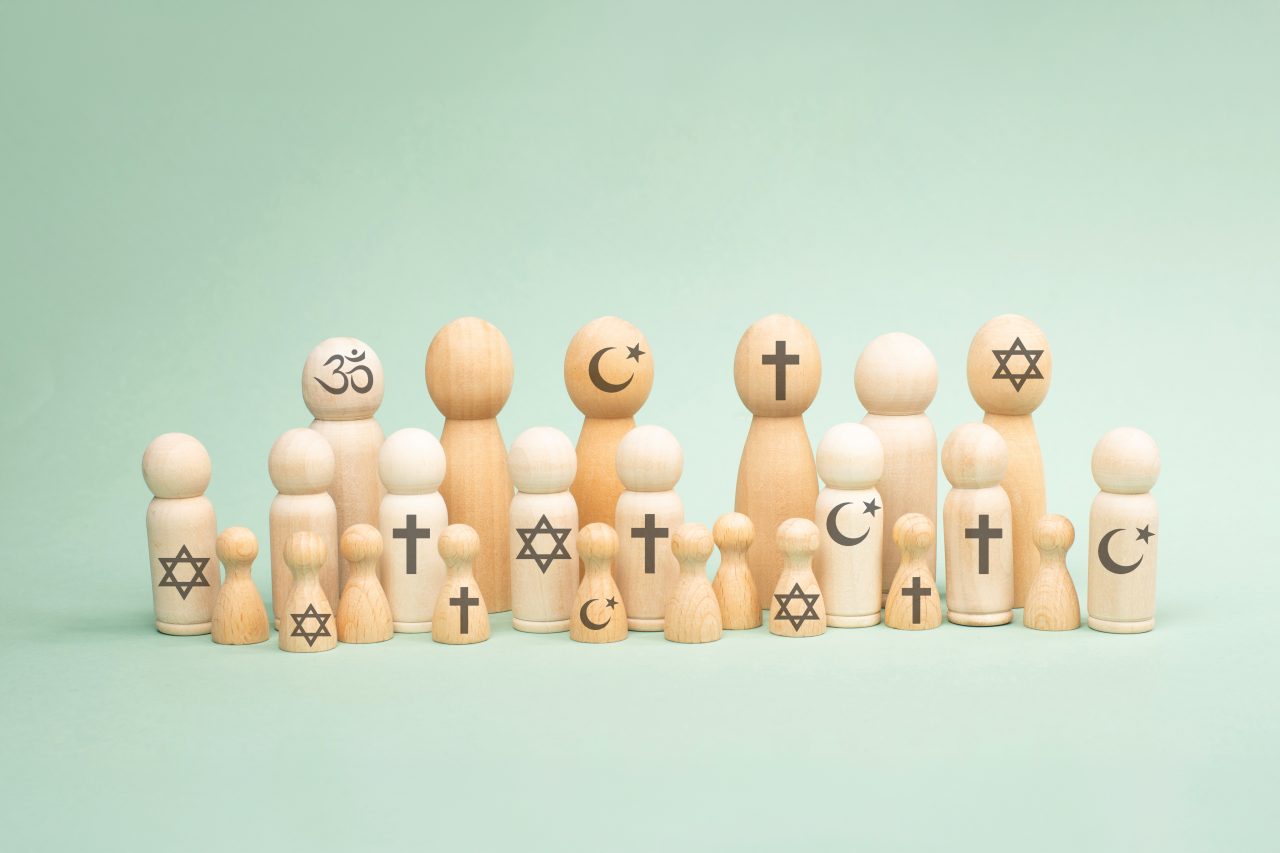 Trefigurer med symboler fra ulike religioner, som kors, halvmåne, davidsstjerne og om-tegn