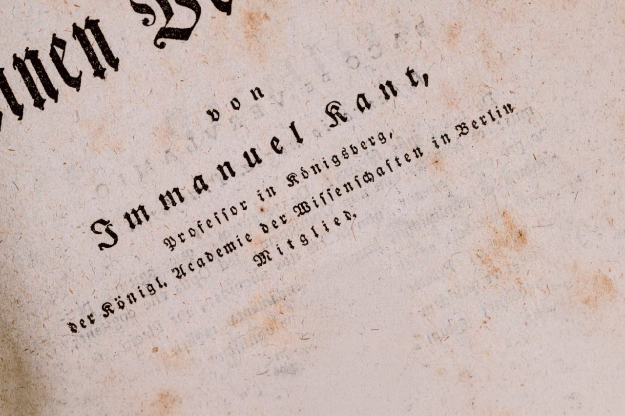 Nærbilde av gammel bokside med gotisk skrift og teksten “Immanuel Kant”.