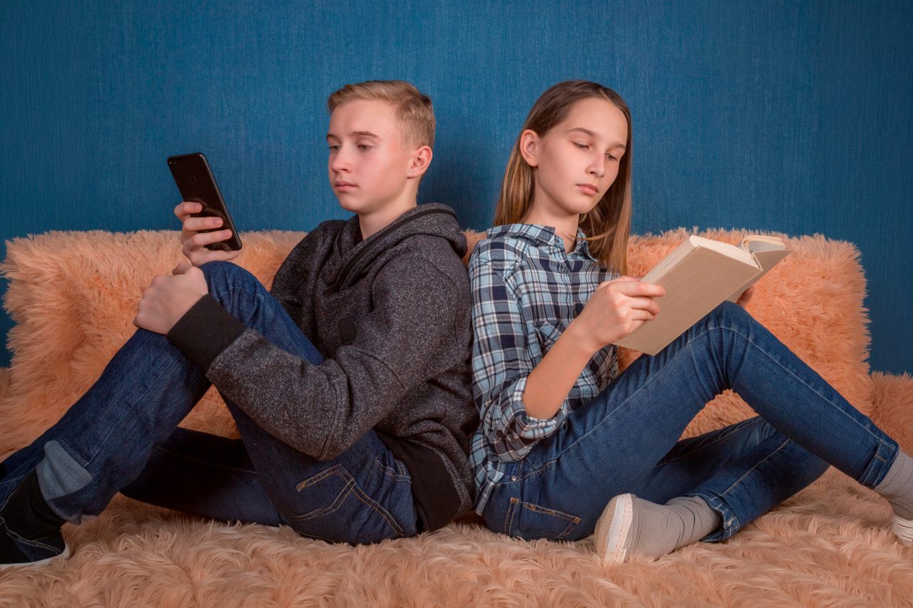 To tenåringer, den ene leser, den andre bruker mobilen