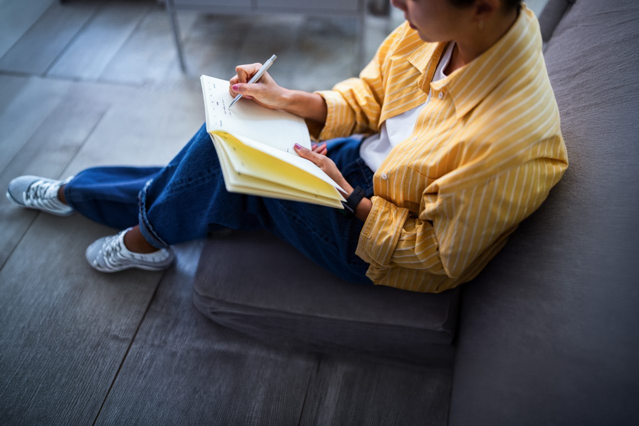 En kvinne som sitter og skriver i en notatbok